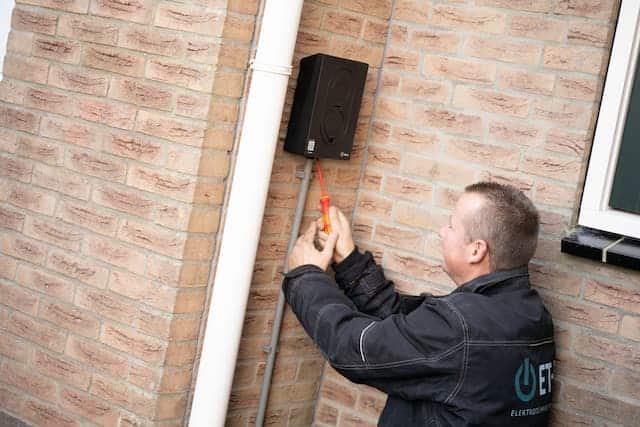 Monteur installeert oplaadunit aan muur.