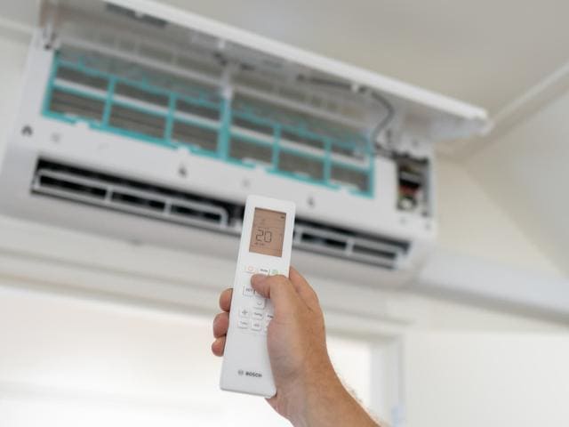 Hand houdt een afstandsbediening voor een airconditioner